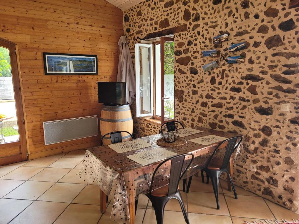 a dining room with a table and chairs and a stone wall at Gîte le Chai in Le Teich