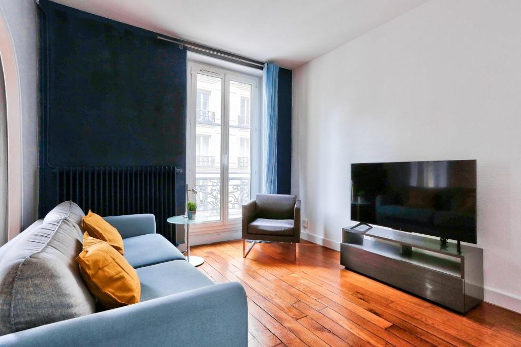 een woonkamer met een bank en een flatscreen-tv bij Appartement Quartier Parc Monceau in Parijs