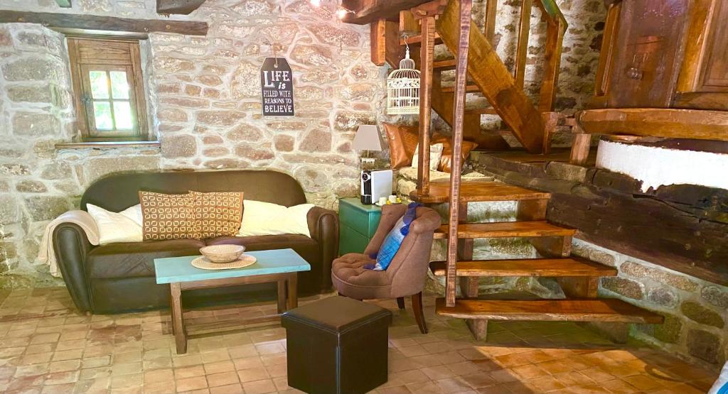 een woonkamer met een bank, een tafel en een trap bij ÉCO-VILLAGE Les Moulins du Duc in Moëlan-sur-Mer