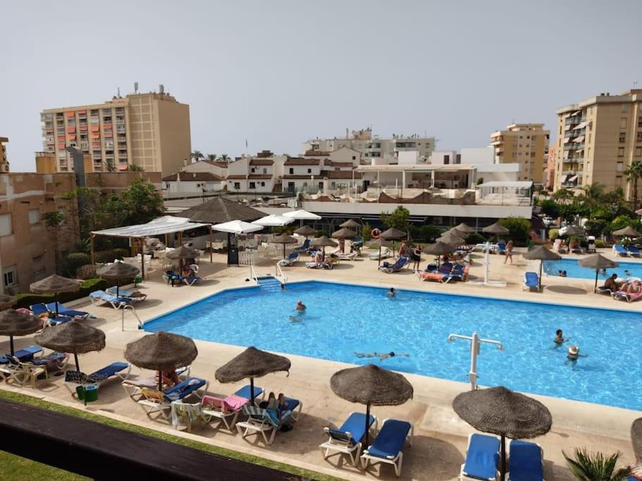 a large swimming pool with chairs and umbrellas at Nogalera con piscina in Torremolinos