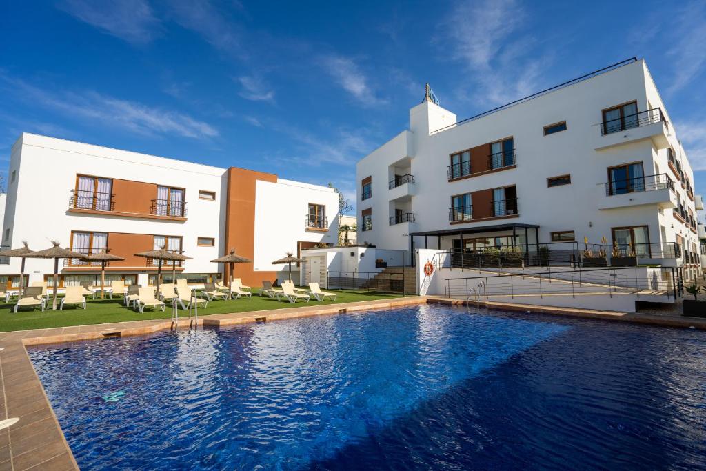 un hotel con piscina frente a un edificio en Hotel Andalussia, en Conil de la Frontera