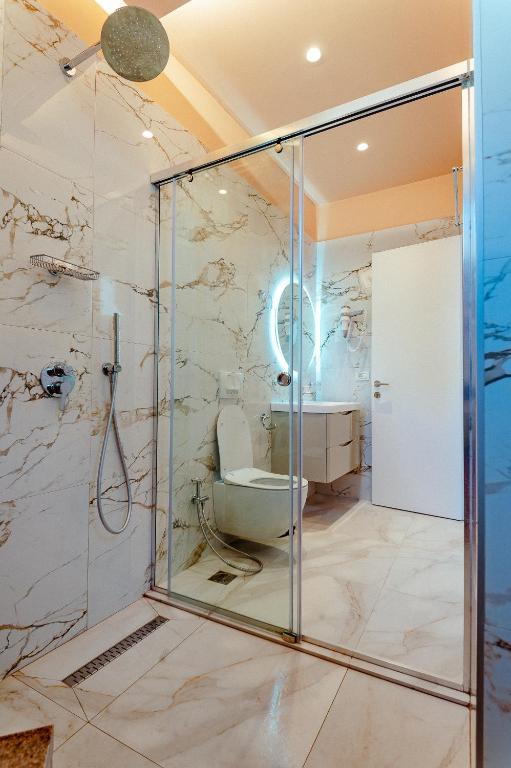 y baño con ducha de cristal y aseo. en Alex Boutique Hotel, en Himare