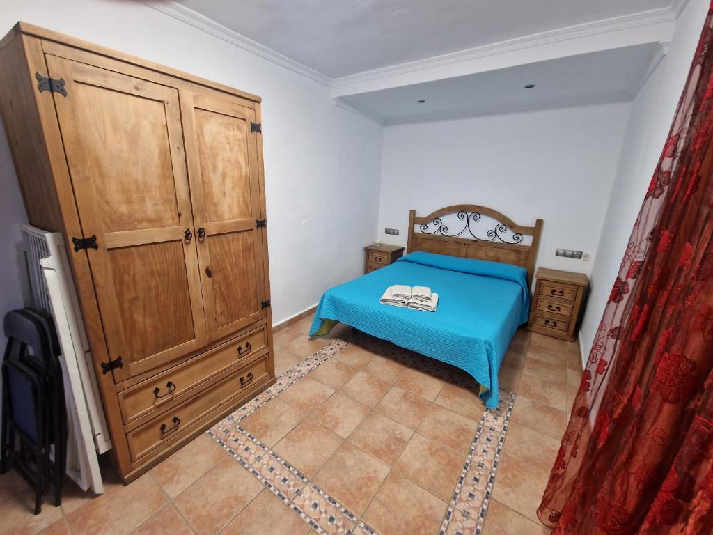 a bedroom with a blue bed and a wooden cabinet at Habitaciones Miramar in Bolonia