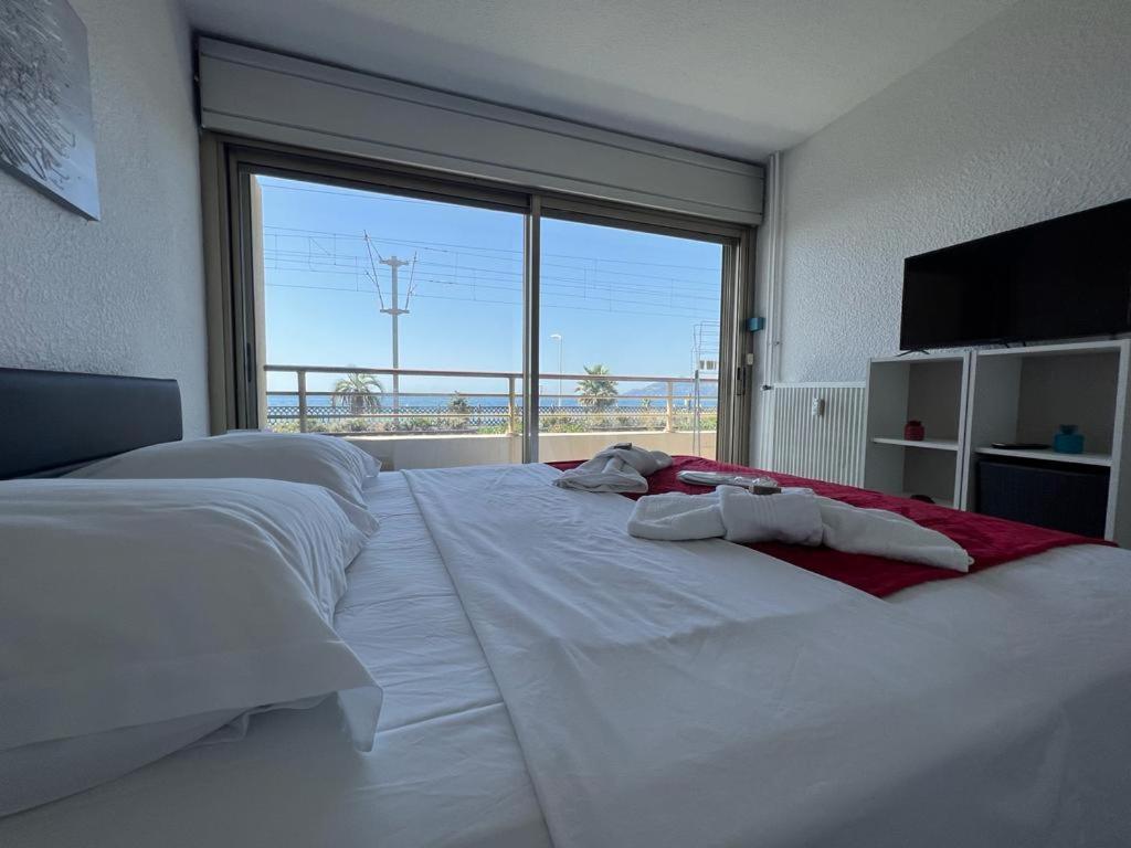 ein großes weißes Bett in einem Zimmer mit einem großen Fenster in der Unterkunft Licorne G14 in Cannes