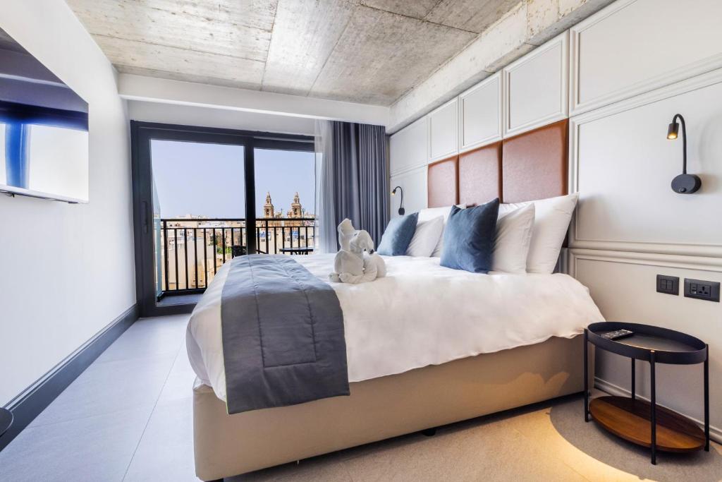 a bedroom with a large bed with a teddy bear on it at The Londoner Hotel Sliema in Sliema