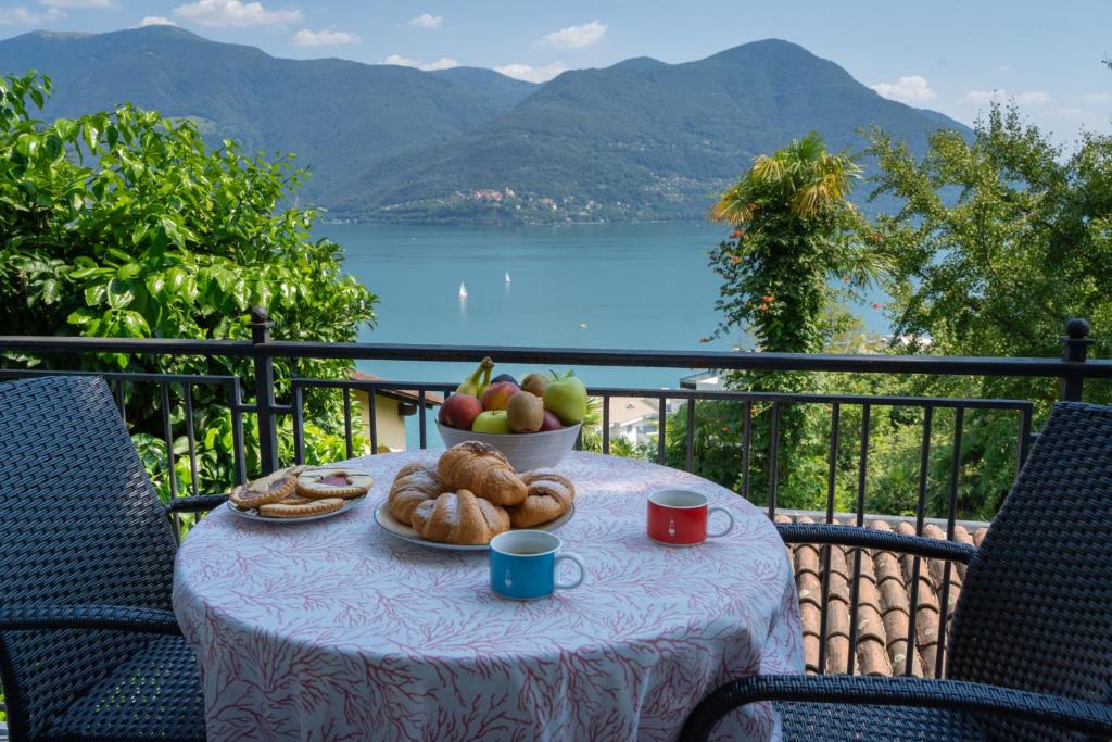 a table with a bowl of fruit and bread on a balcony at Lake Paradise in Brissago