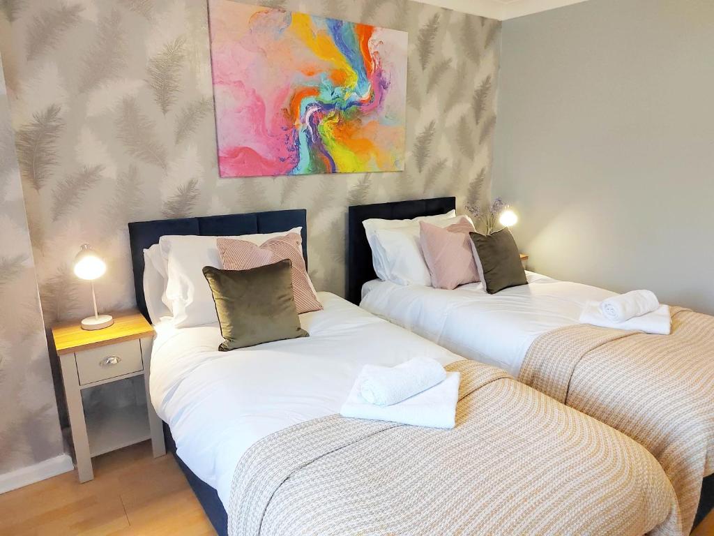 2 Single Beds, 1 BR Apartment في نيوماركت: سريرين توأم في غرفة مع لوحة على الحائط