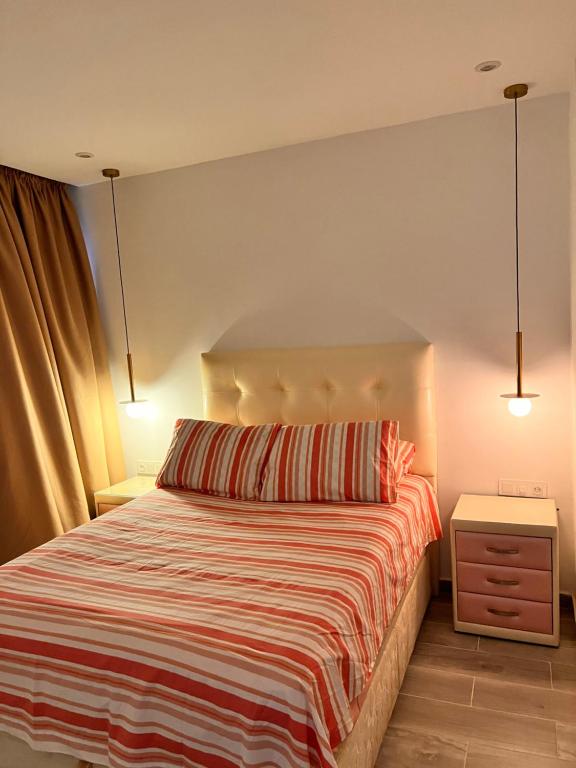 een slaapkamer met een bed met een gestreepte deken bij شقة في المضيق in M'diq