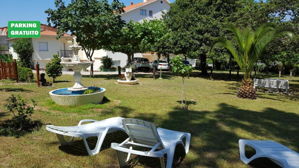 a yard with a white chair and a fountain at Hotel La Costera in A Lanzada