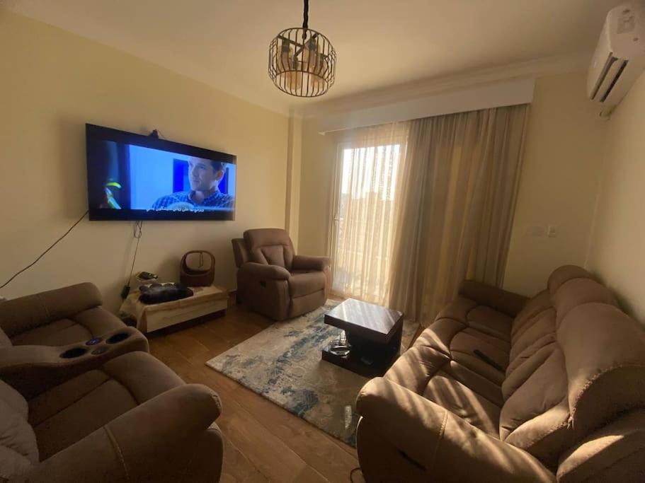 a living room with two couches and a flat screen tv at A gorgeous furnished 3 BDs apt in 6th Of October