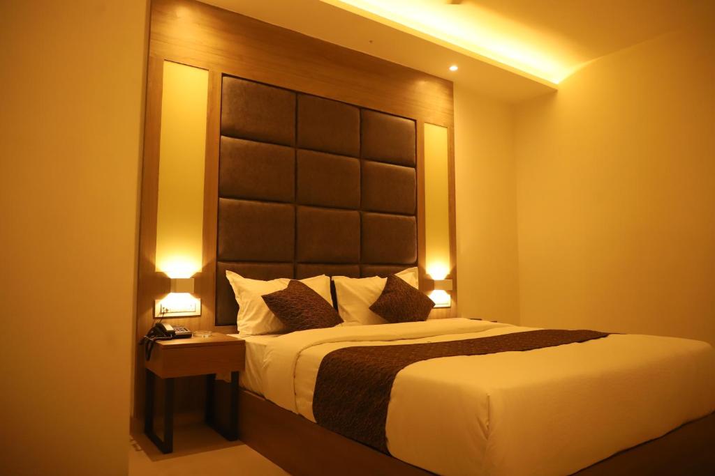 a bedroom with a large bed with two lights on at Hotel Sai Pritam in Mumbai