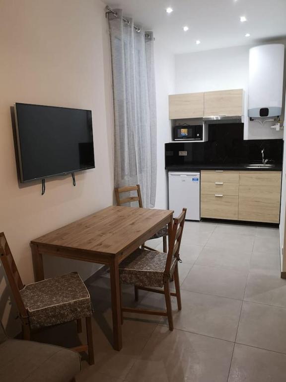 Il comprend une cuisine avec une table et des chaises en bois ainsi qu'une télévision. dans l'établissement maison de papa, à Nice