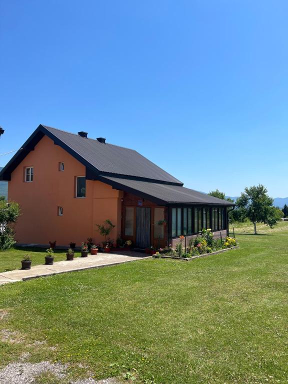 a house with a green lawn in front of it at Apartments Marija in Vrelo Koreničko