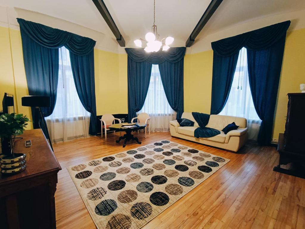 Riverside Old Town Spacious One Bedroom Apartment في ريغا: غرفة معيشة مع ستائر زرقاء وأريكة وسجادة