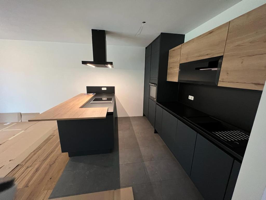 PR Arpartment في Lenzing: مطبخ مع خزائن سوداء وقمة منضدة خشبية