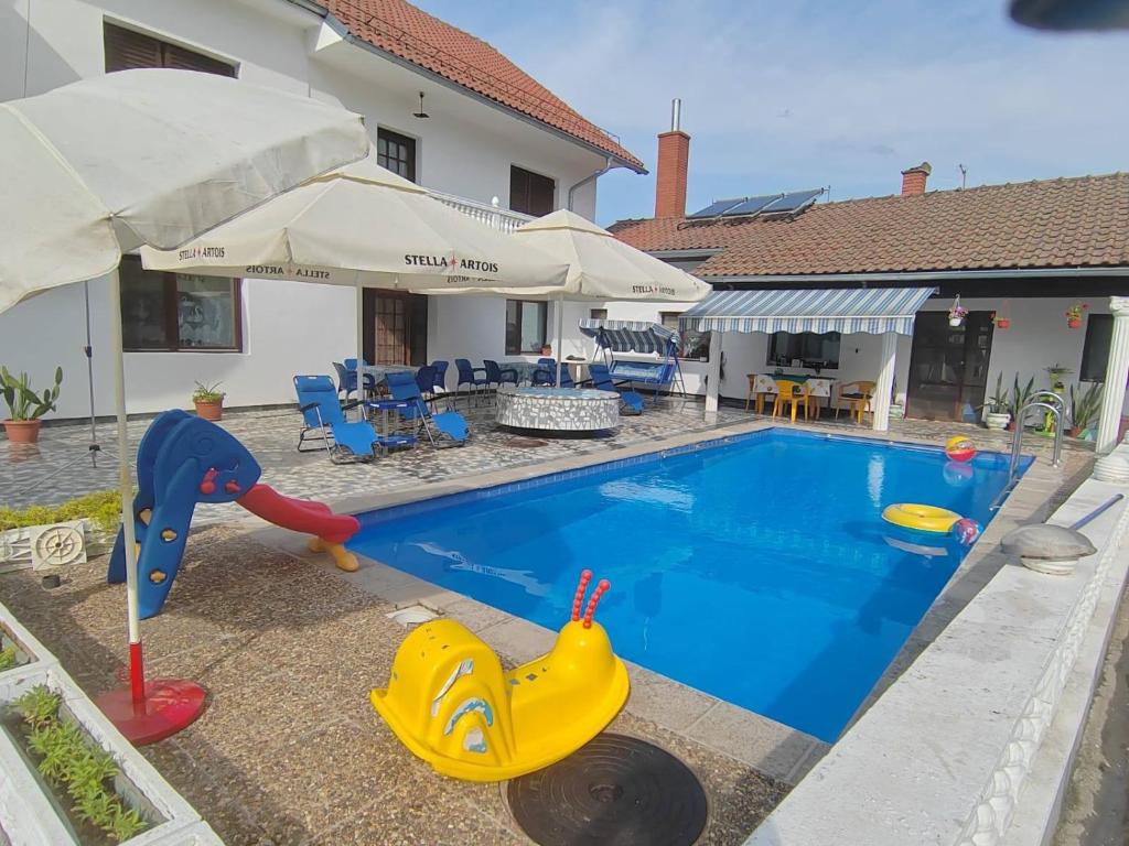 a swimming pool with a toy boat next to a house at Vila Jovana A in Rogljevo