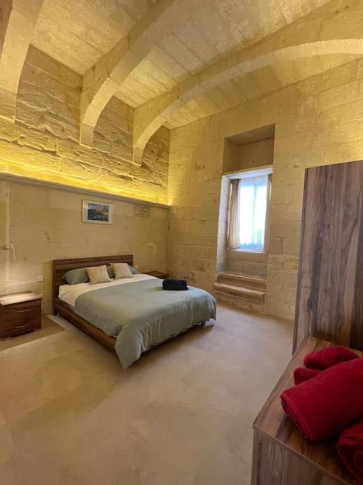 una grande camera da letto con un grande letto in un edificio di Ta' Cikku Farmhouse a Xagħra