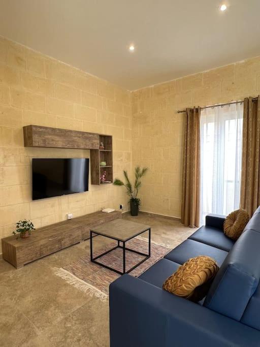 un soggiorno con un divano blu e una TV di Ta' Cikku Farmhouse a Xagħra