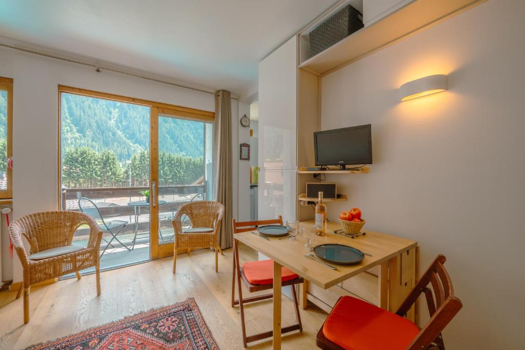 uma sala de estar com uma mesa e cadeiras e uma grande janela em Les Marmottes d'Argentière - Happy Rentals em Chamonix-Mont-Blanc