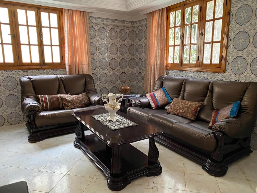 a living room with two leather couches and a coffee table at Rez-de-jardin à Mohammedia in Mohammedia