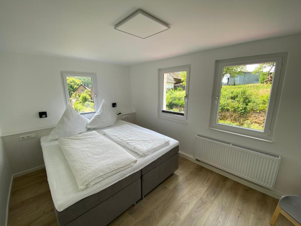 a bedroom with a bed and two windows at Ferienhaus Römer in Wirft