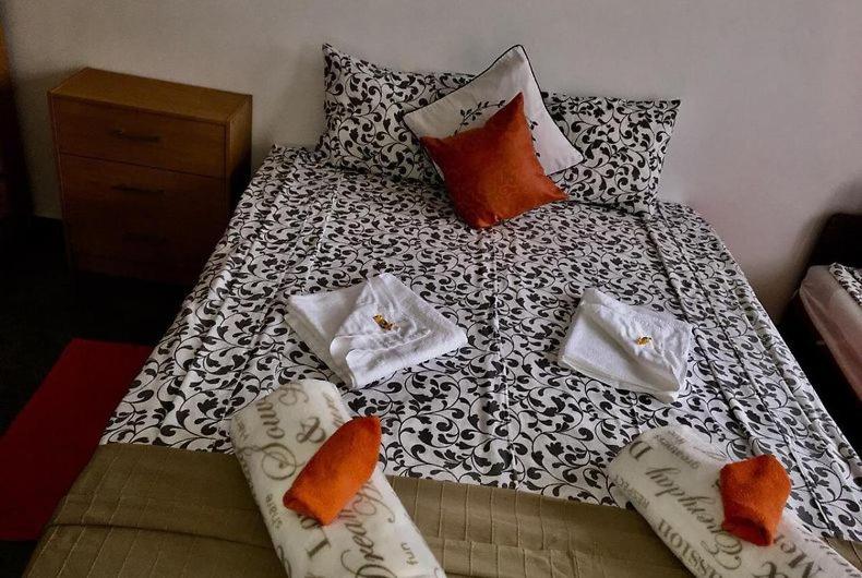 Una cama con sábanas y almohadas blancas y negras. en Fenyves Szálló, en Balatonfenyves