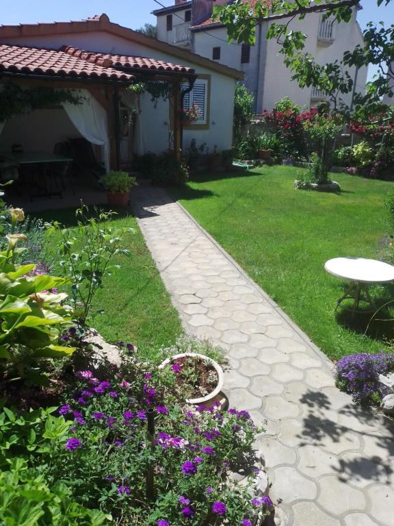 a garden with purple flowers and a table and a patio at Bungalow Tribunj in Tribunj