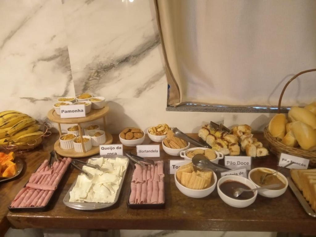 a table filled with different types of pastries and desserts at Pousada GPC in Macaé