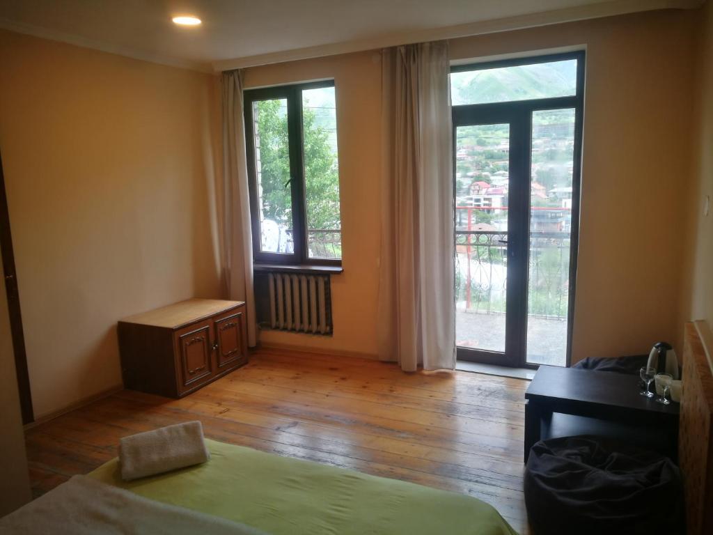 a bedroom with a bed and a desk and windows at Belas guesthouse in Stepantsminda