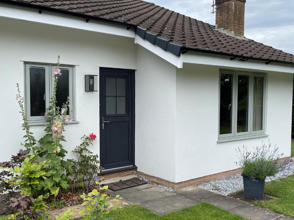 une maison blanche avec une porte noire dans l'établissement Fir Tree Cottage, à Chester