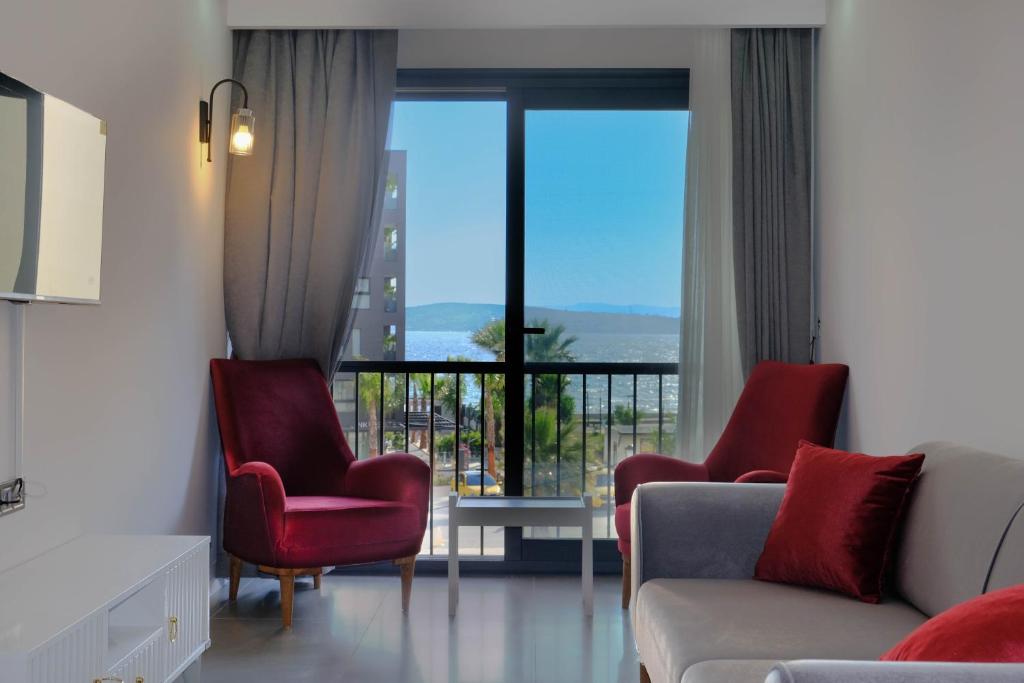 een woonkamer met een bank en stoelen en een balkon bij Mercan Suites Ilıca in Çeşme
