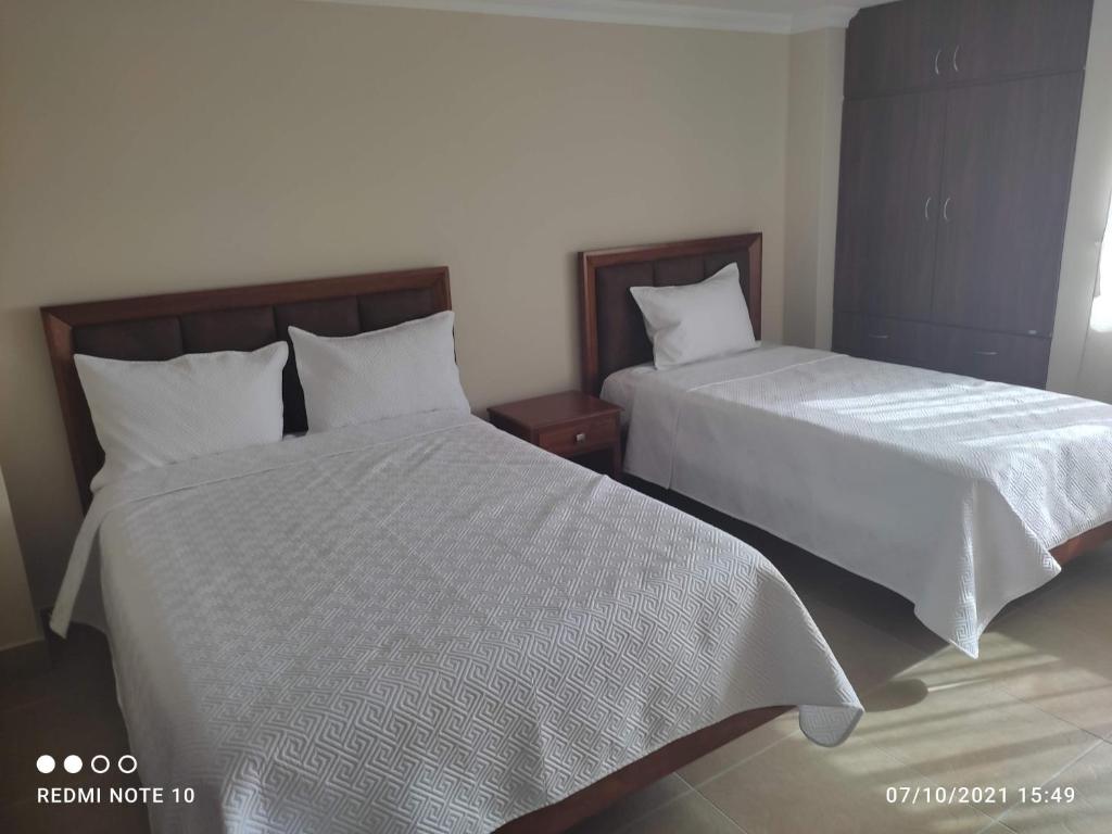 dos camas sentadas una al lado de la otra en un dormitorio en HOTEL SHANGHAI CITY, en Ibarra