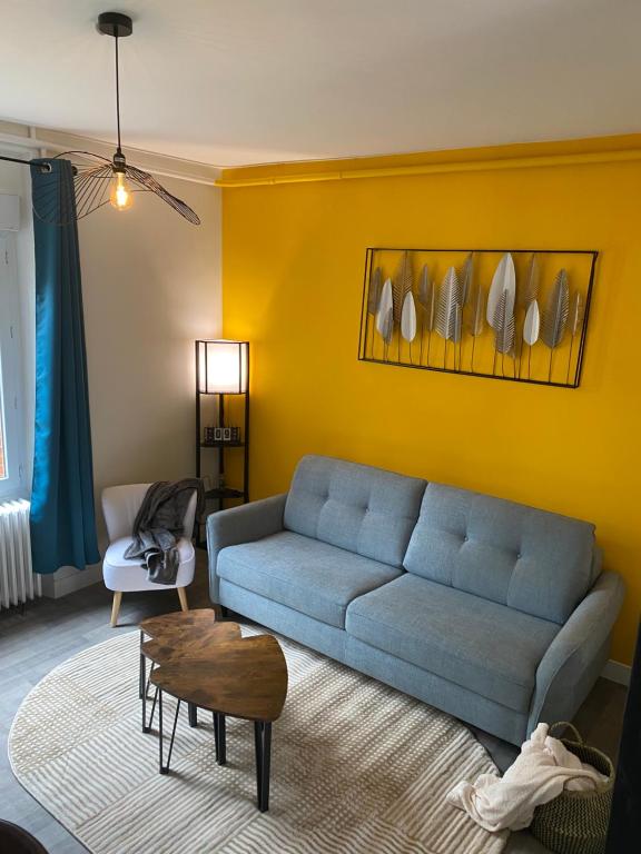 uma sala de estar com um sofá azul e uma parede amarela em Maison les 3 fées , 3 chambres, Chamerolles em Courcy-aux-Loges