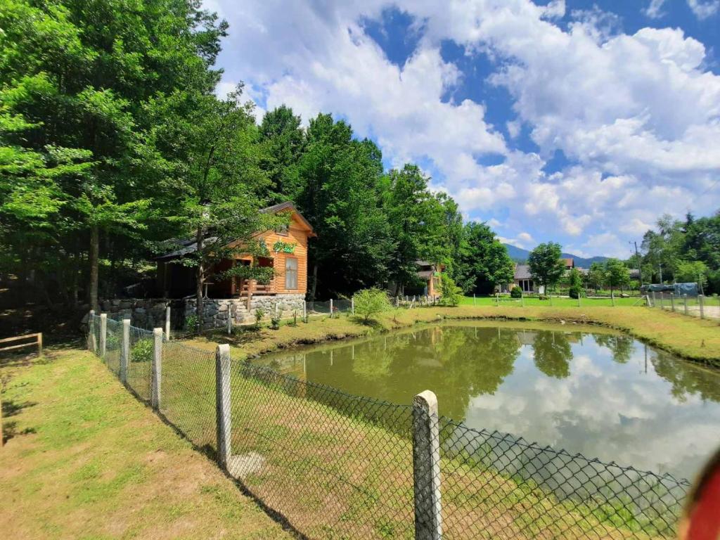 una valla alrededor de un estanque frente a una casa en Bungalovi Menzil en Zavidovići
