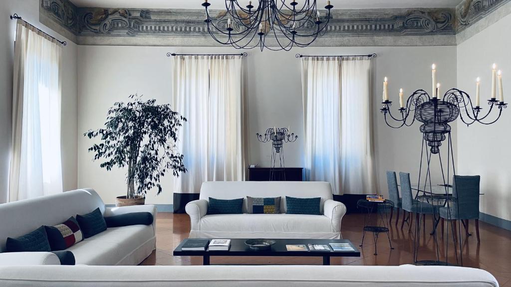 un soggiorno con divano bianco e lampadario pendente di Hotel Palazzo Piccolomini a Orvieto
