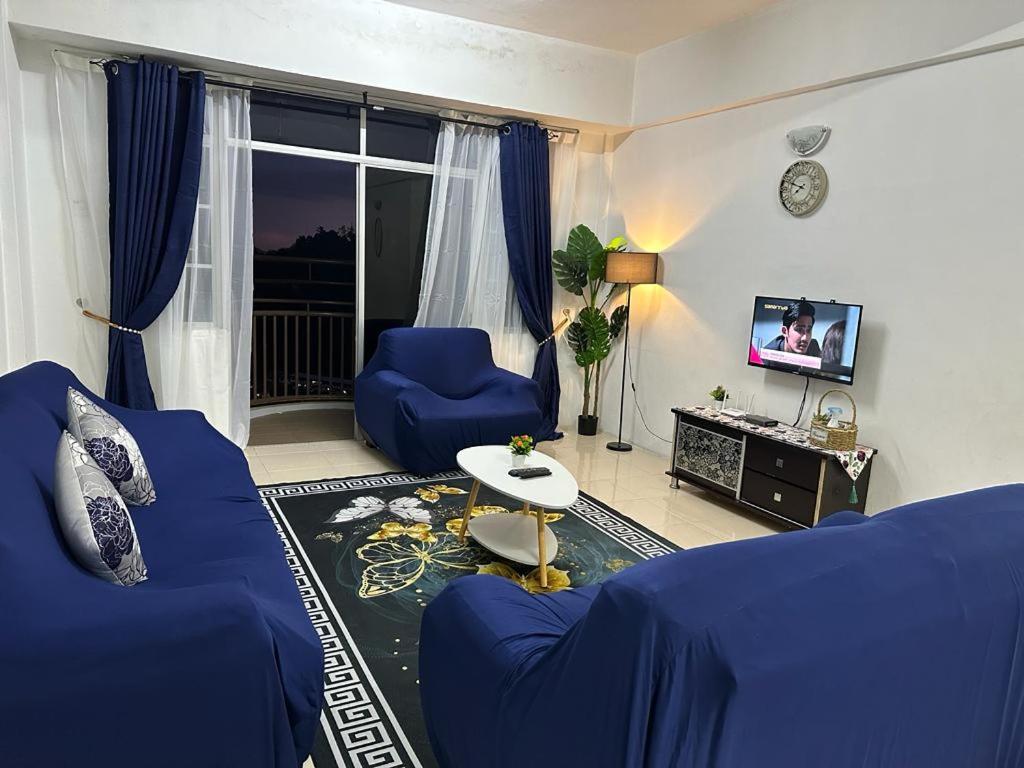 uma sala de estar com um sofá azul e uma televisão em D'CAMERON MUSLIM HOMESTAY em Brinchang