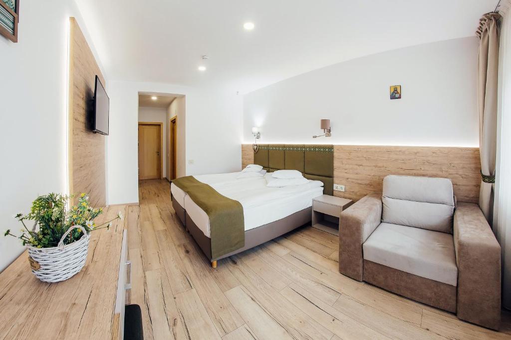a bedroom with a bed and a couch and a chair at Blumenhof Bucovina in Voronet