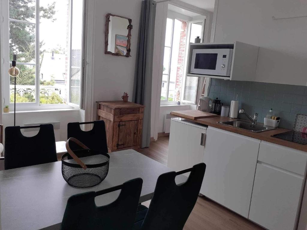 ランシューにあるStudio 400m de la merの白いキャビネット、テーブルと椅子付きのキッチンが備わります。