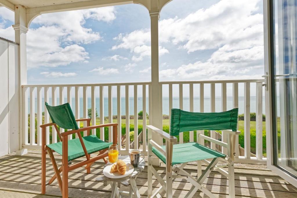 two chairs and a table on a porch with the ocean at Luna's Seaview Apartment Sleeps 4 Parking Beach in Kent