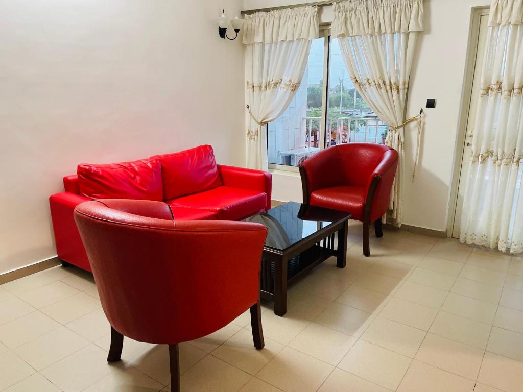 een woonkamer met een rode bank en 2 stoelen bij Espace Scyca in Abomey-Calavi