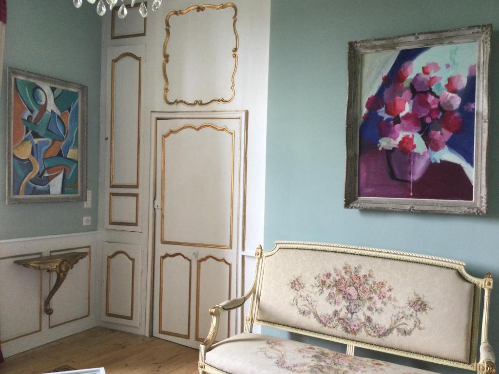 a room with a chair and a painting on the wall at L’orangerie du Général in Saint-Jean-dʼAngély