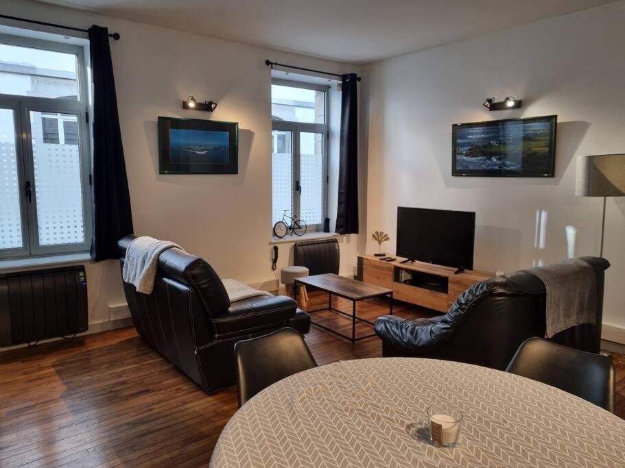 a living room with leather chairs and a television at Grand appartement près de la Cathédrale de Quimper in Quimper