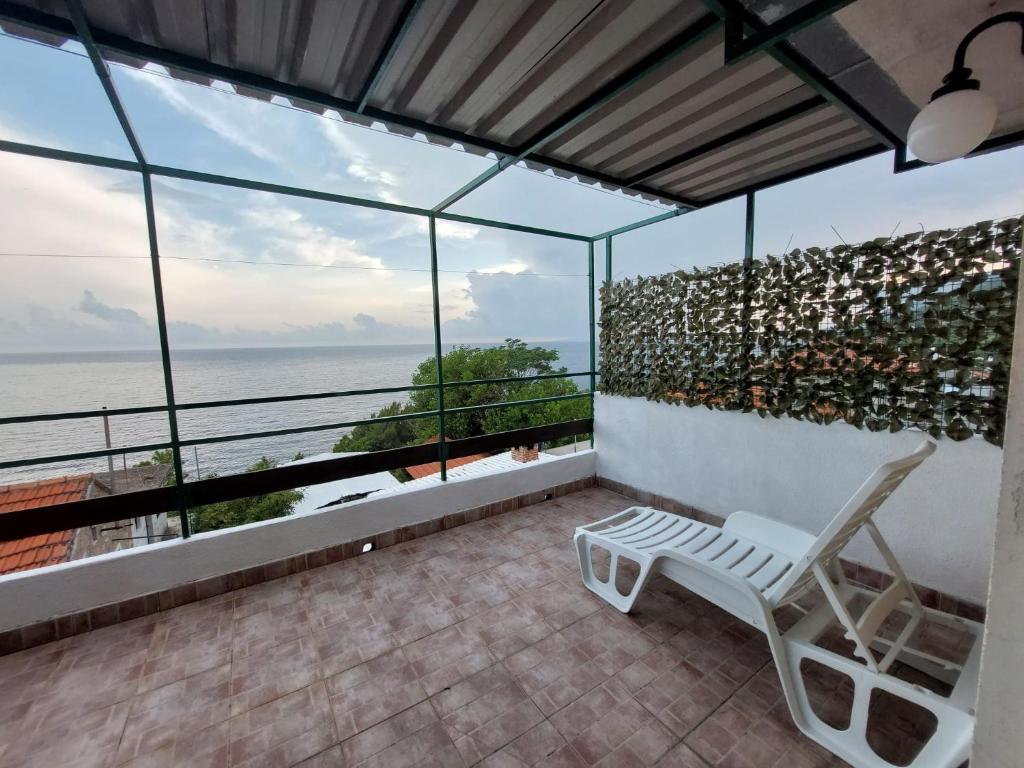 une chaise blanche sur un balcon avec vue sur l'océan dans l'établissement Apartmani Kapiton, à Hvar