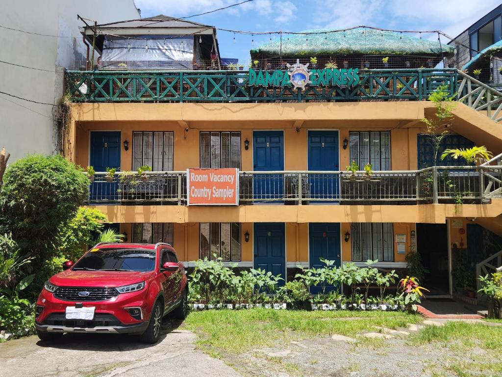 czerwony samochód zaparkowany przed budynkiem w obiekcie Country Sampler Inn w mieście Tagaytay