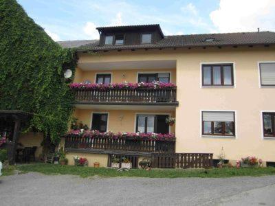 ein großes Gebäude mit einem Balkon mit Blumen darauf in der Unterkunft Ferien auf dem Bauernhof in Moosbach