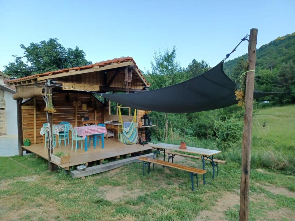 une cabane en rondins avec une table et un hamac dans l'établissement SIMBIOSIS. Agri Cultur'Art Camp, à Pontinvrea