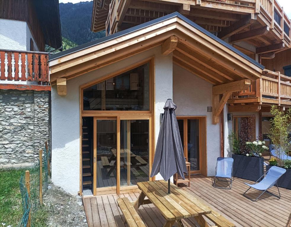 una casa con ombrellone e sedie su una terrazza di Chalet Bio Corti Spa 4 personnes a Champagny-en-Vanoise