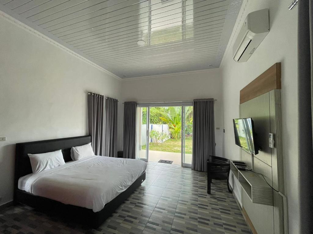 een slaapkamer met een bed en een flatscreen-tv bij Pondok Sahang Cottages in Muntok