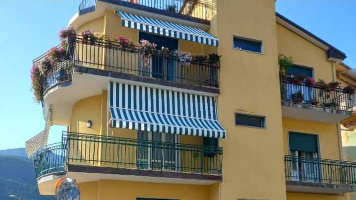 ein gelbes Gebäude mit Balkonen mit Blumen darauf in der Unterkunft La Casa di Walter in Levanto
