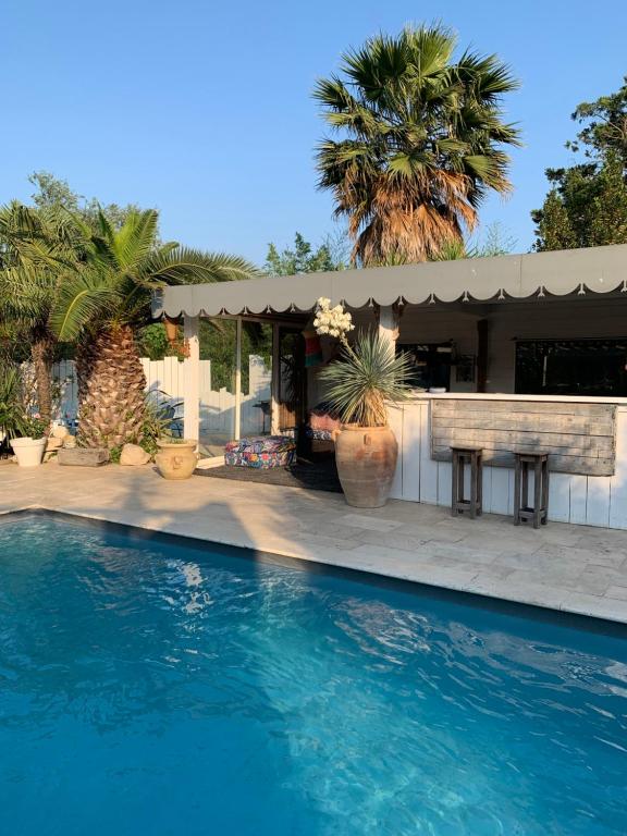 a swimming pool in front of a house with palm trees at La villa Paloma in Sylvéréal